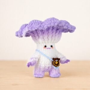 Crocheted white mushroom doll with a ruffled purple cap, standing on a wooden surface with a small brown crossbody bag